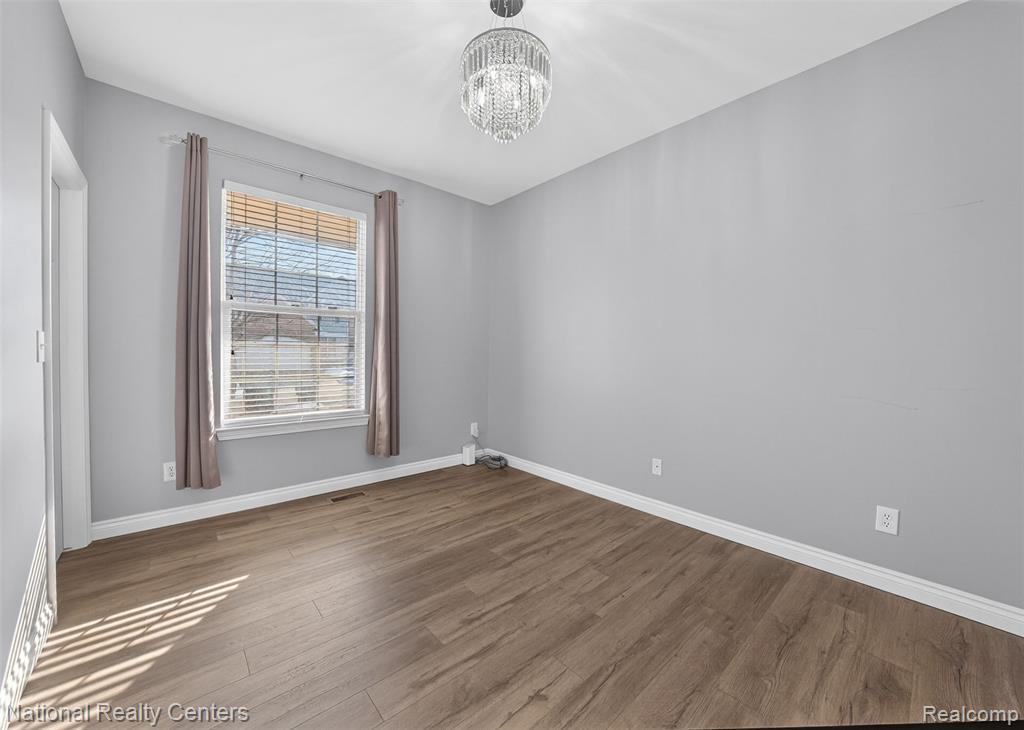 Unfurnished room featuring wood finished floors and hanging lights