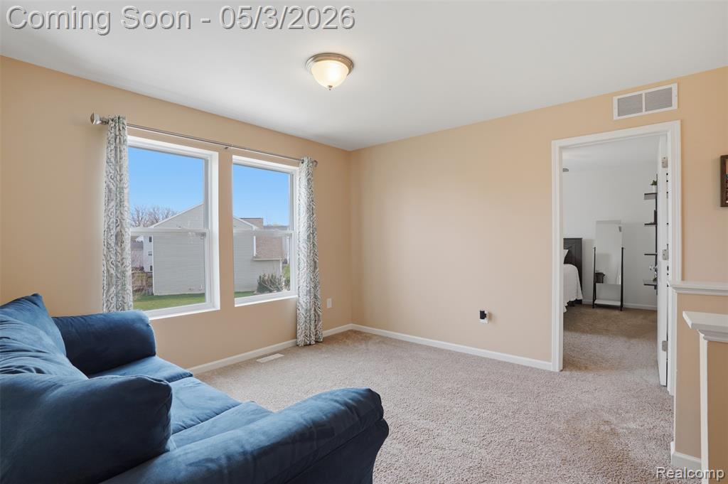 Living area featuring light carpet and baseboards