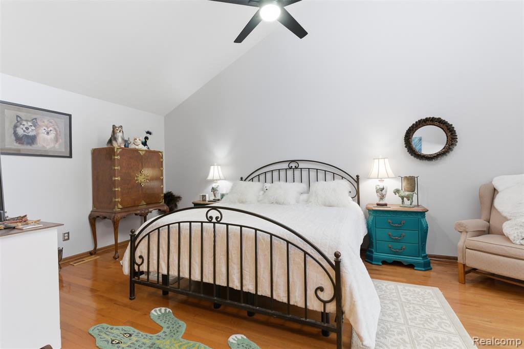 Bedroom featuring light wood-style floors, lofted ceiling, and ceiling fan