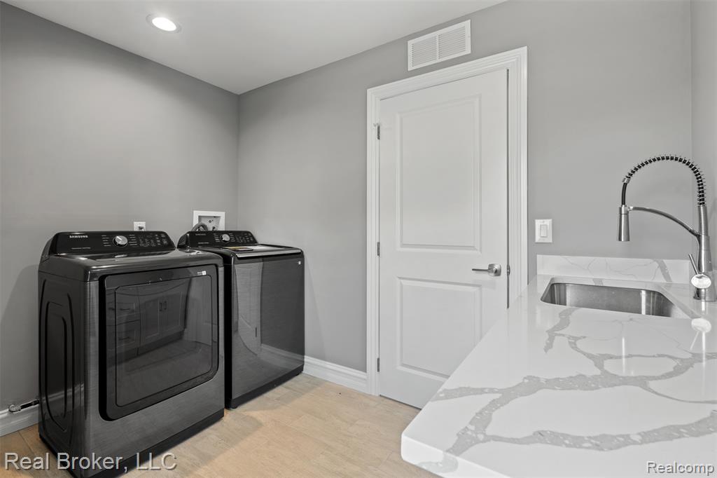 Washroom with light wood-style flooring, separate washer and dryer, and recessed lighting