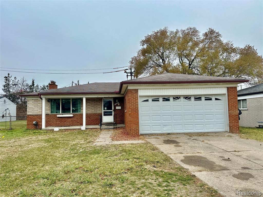 Ranch-style house featuring brick siding, a front yard, driveway, a chimney, and a garage
