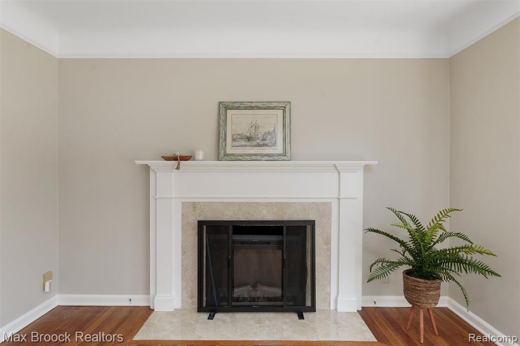 Detailed view of fireplace w. electric insert, wood finished floors, and crown molding