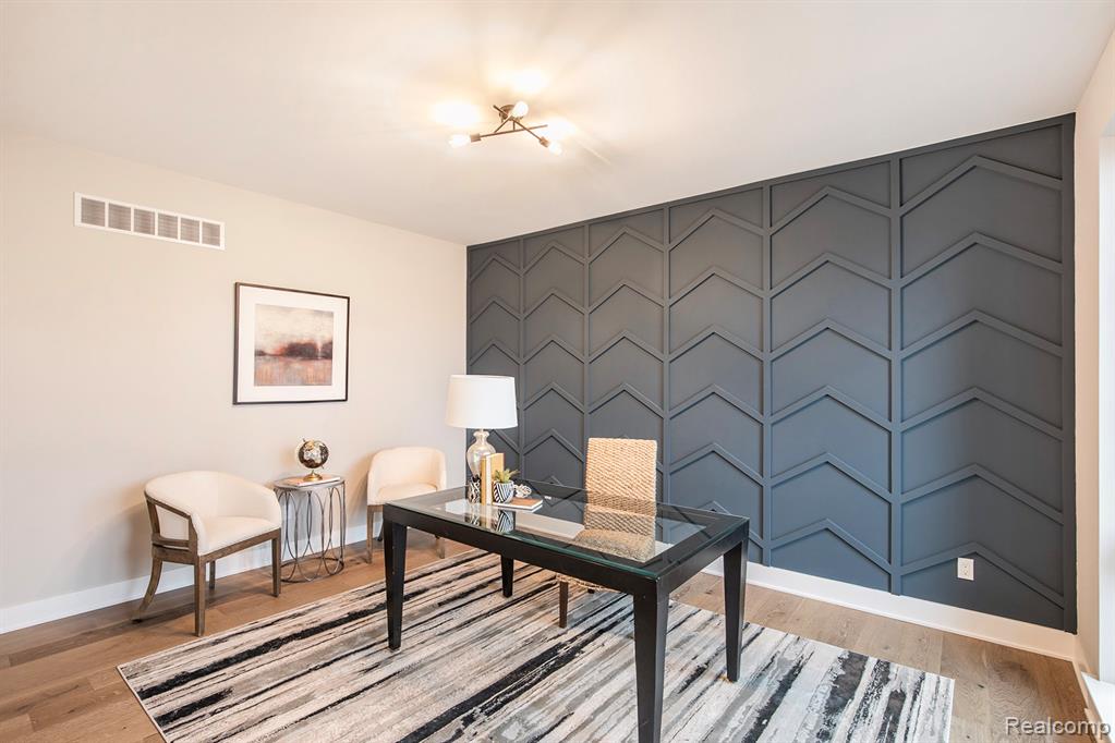 Office with an accent wall and light wood-type flooring
