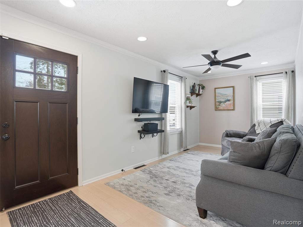Living room with crown molding, light wood finished floors, ceiling fan, and recessed lighting
