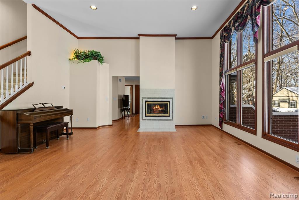 Living area featuring a fireplace, light wood-style floors, recessed lighting, crown molding, and stairs
