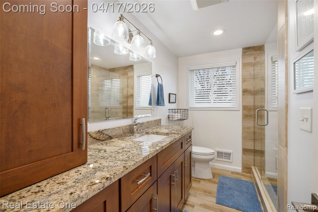 Full bath with vanity, a shower stall, light wood finished floors, and recessed lighting