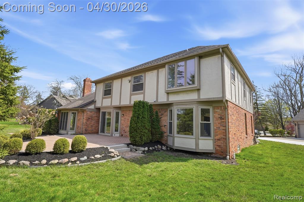 Back of property with brick siding, a yard, stucco siding,