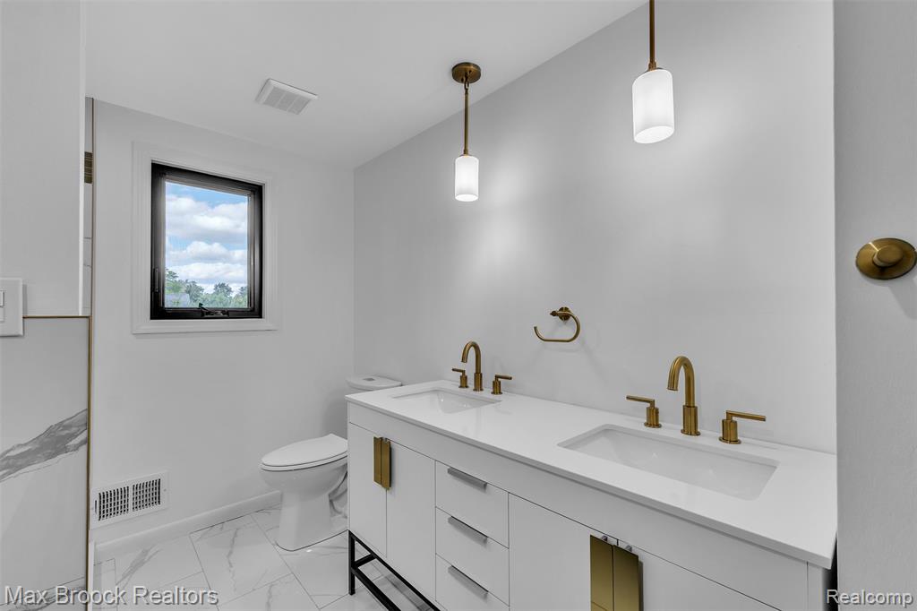 Bathroom featuring double vanity and light marble finish floors