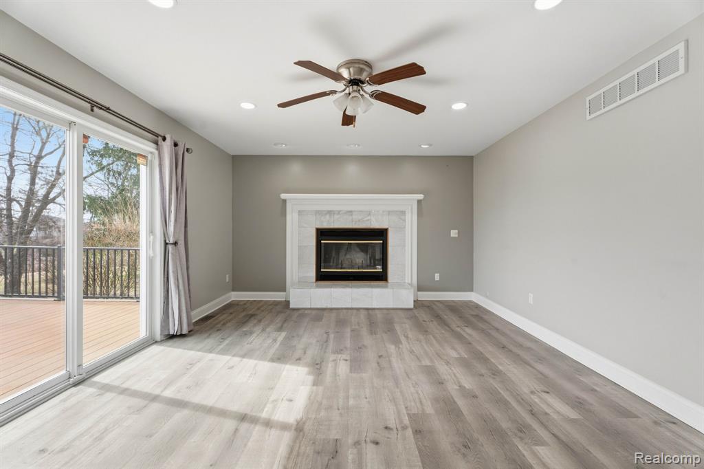 Unfurnished living room featuring ceiling fan, light wood-style floors, a tiled fireplace, and recessed lighting