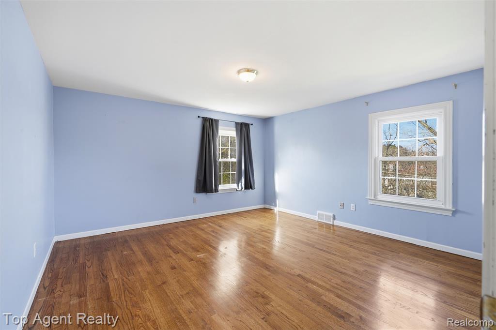 Unfurnished bedroom with two closets and hardwood / wood-style floors