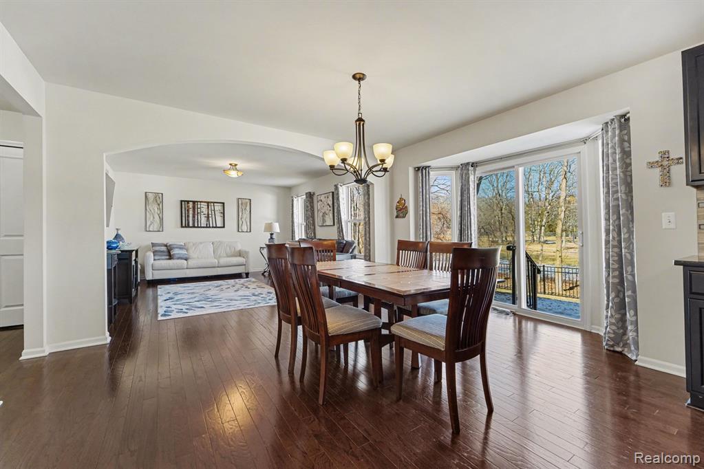 Dining room featuring arched walkways, dark wood-style flooring, and suspended lighting
