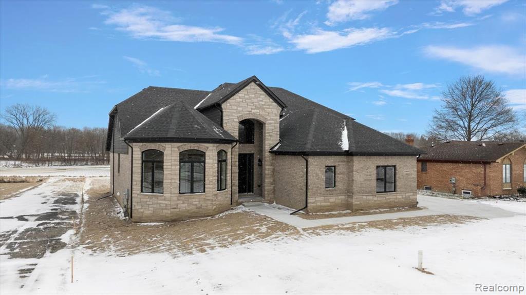 View of front of home featuring stone siding and a shingled roof