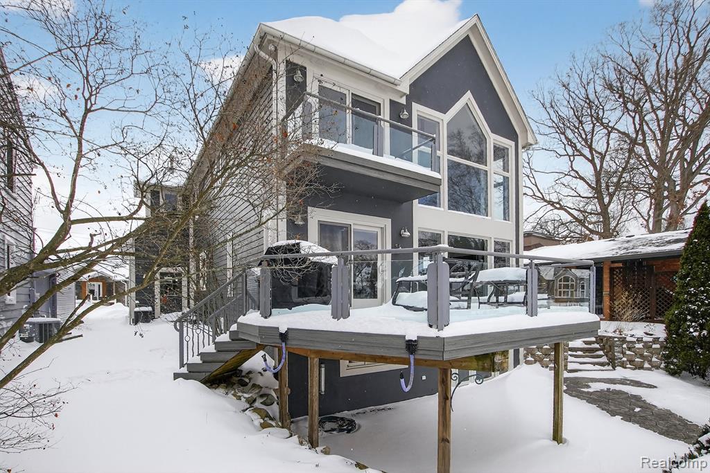 Rear view of house with stucco siding, a balcony, a patio area, and french doors