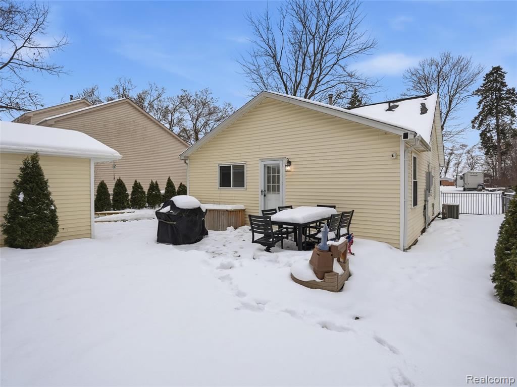 Snow covered back of property featuring outdoor dining space