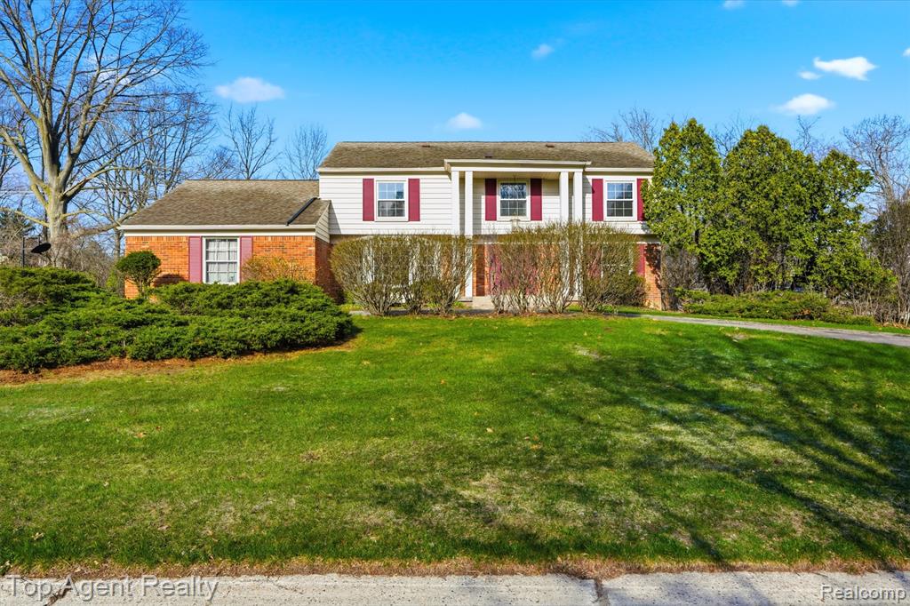 View of side of property featuring brick siding, asphalt driveway, and an attached garage