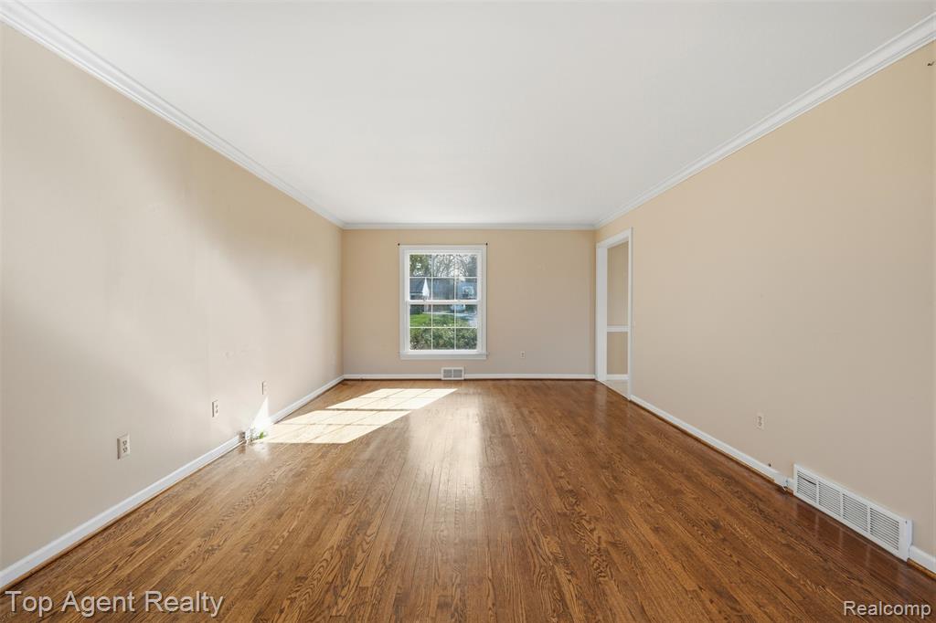 Empty room featuring wood finished floors and ornamental molding