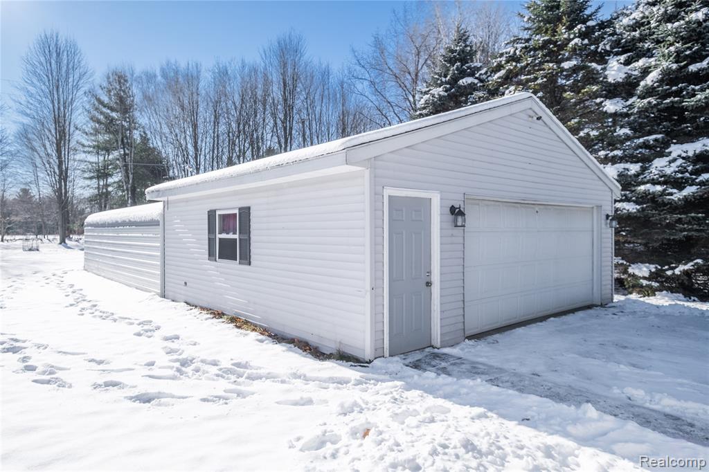 Snow covered garage with a detached garage