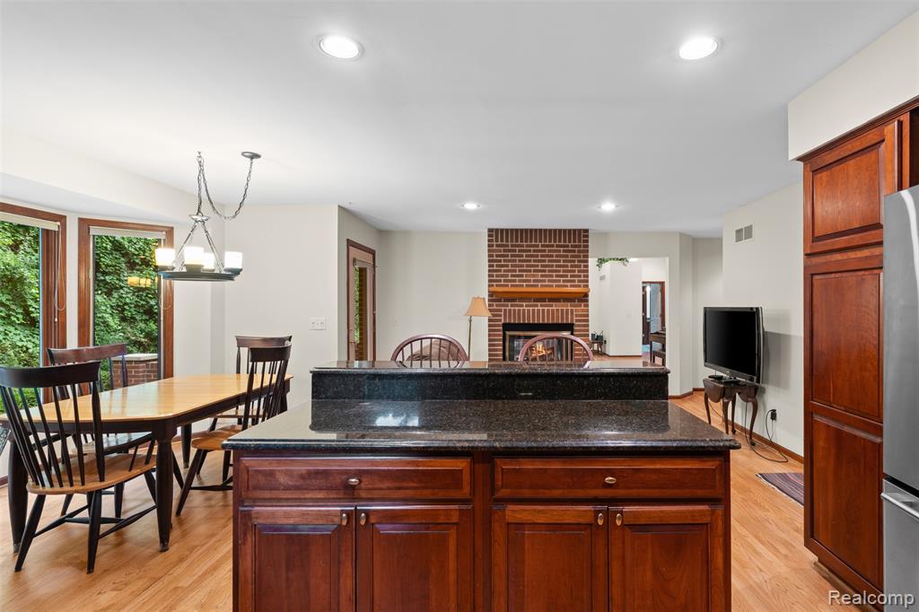 Kitchen featuring dark stone countertops, a fireplace, pendant lighting, light wood finished floors, and recessed lighting