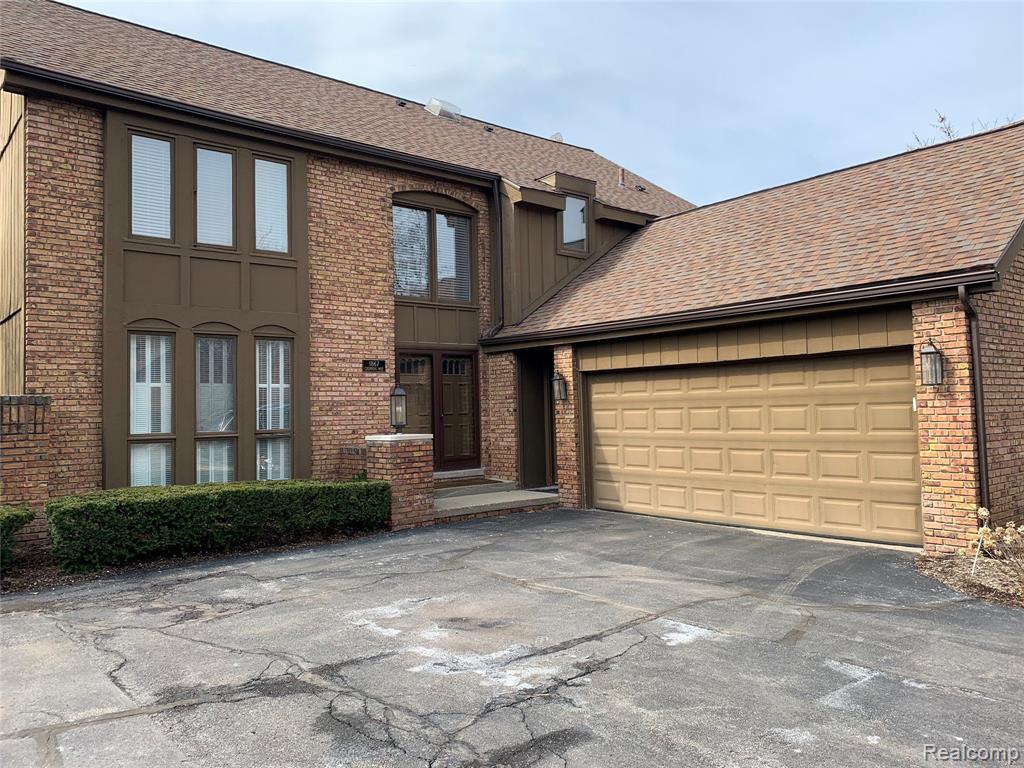 Brick exterior featuring a two-car garage with a panel door, multi-pane windows, and a prominent front entry with double doors