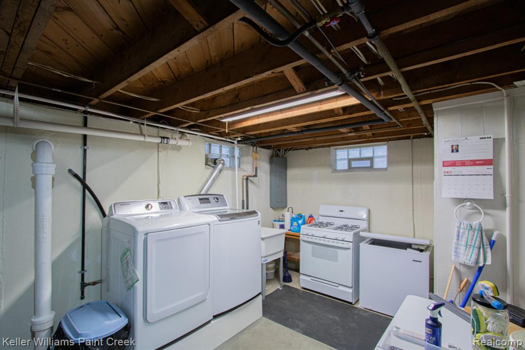 Laundry area with washing machine and dryer, concrete floors, and electric panel