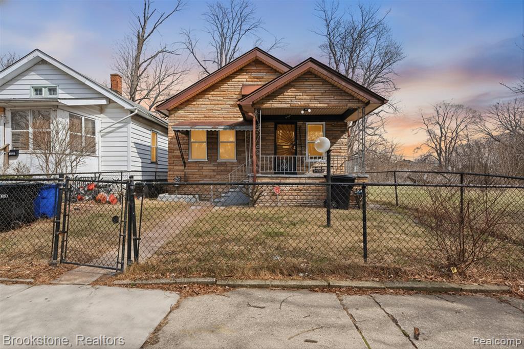 View of front of home with a gate, a fenced front yard, and a porch