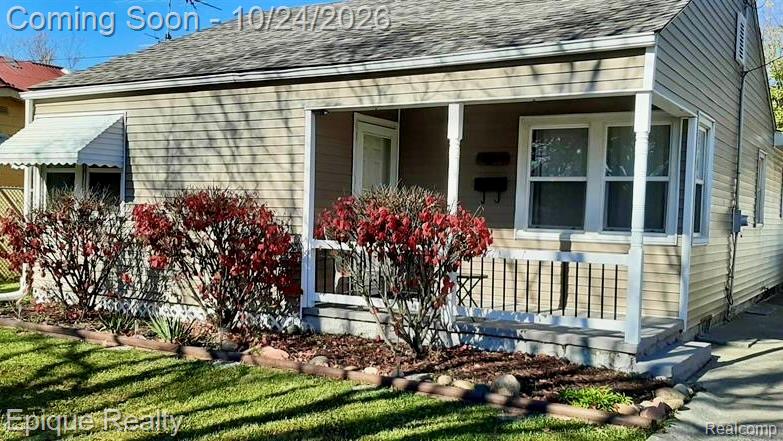 Exterior featuring horizontal siding, a covered front porch with white railing, and a window awning