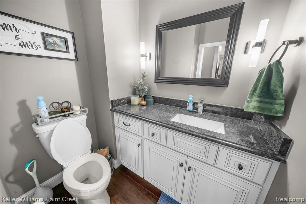 Half bath featuring vanity and dark wood-type flooring