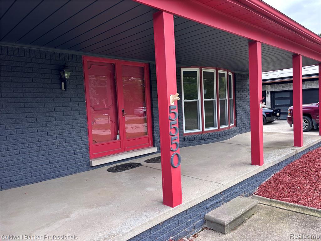 Front Doorway to property featuring brick siding and a porch