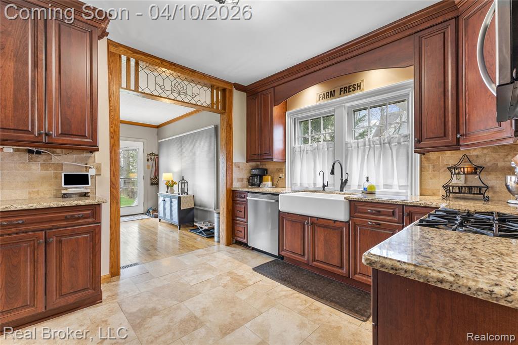 Kitchen with backsplash, light stone countertops, stainless steel appliances, and crown molding