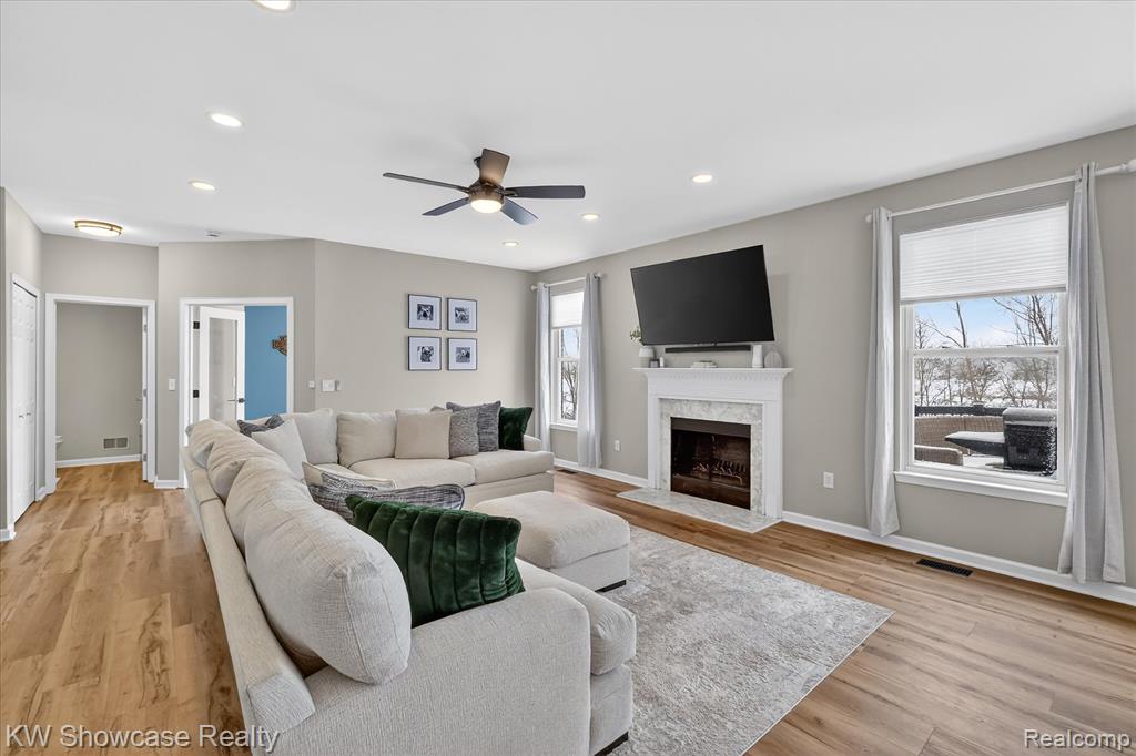 Dining room featuring a fireplace, ceiling fan, light wood-type flooring, recessed lighting, and a chandelier