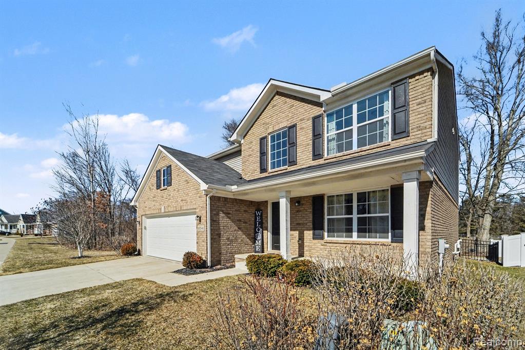 Traditional home with a porch, concrete driveway, and brick siding