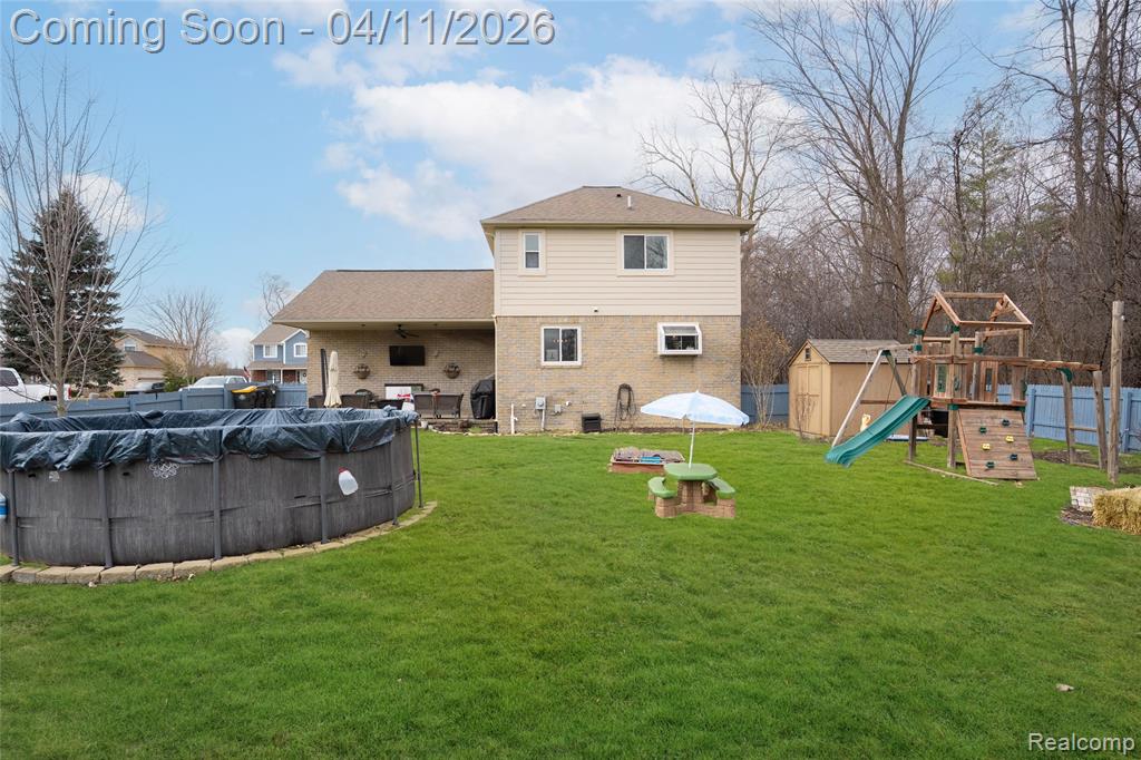 Rear view of house featuring a storage shed, a playground, and brick siding