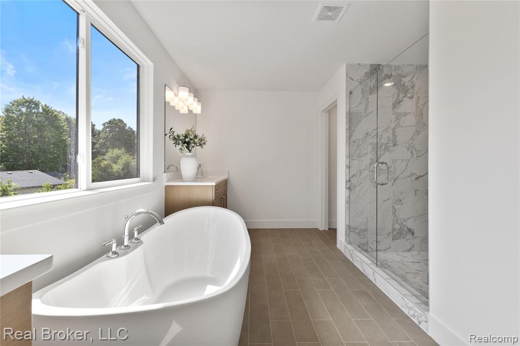 Full bathroom with vanity, a freestanding bath, and a marble finish shower