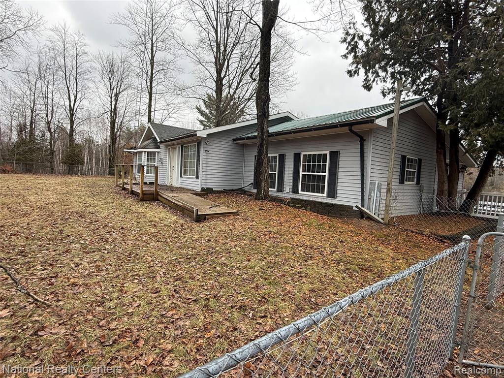 View of front facade with a metal roof and a fenced backyard