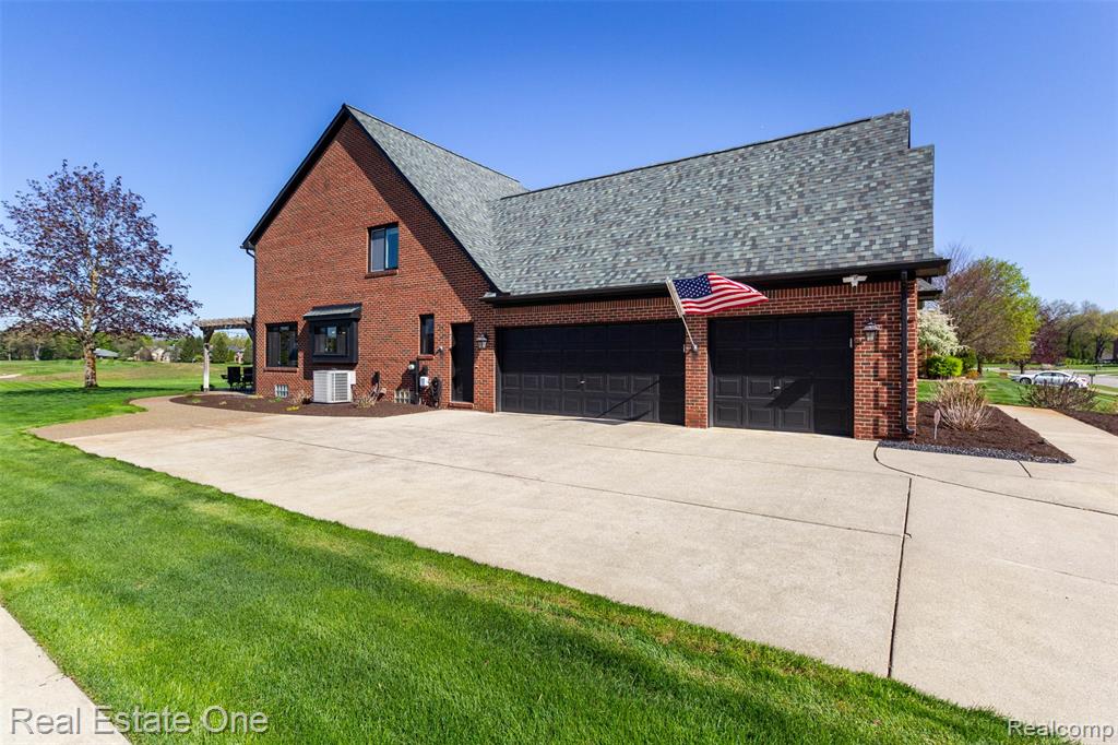 View of side of property featuring a 3 car garage, driveway, and an aggregate walkway to rear patio