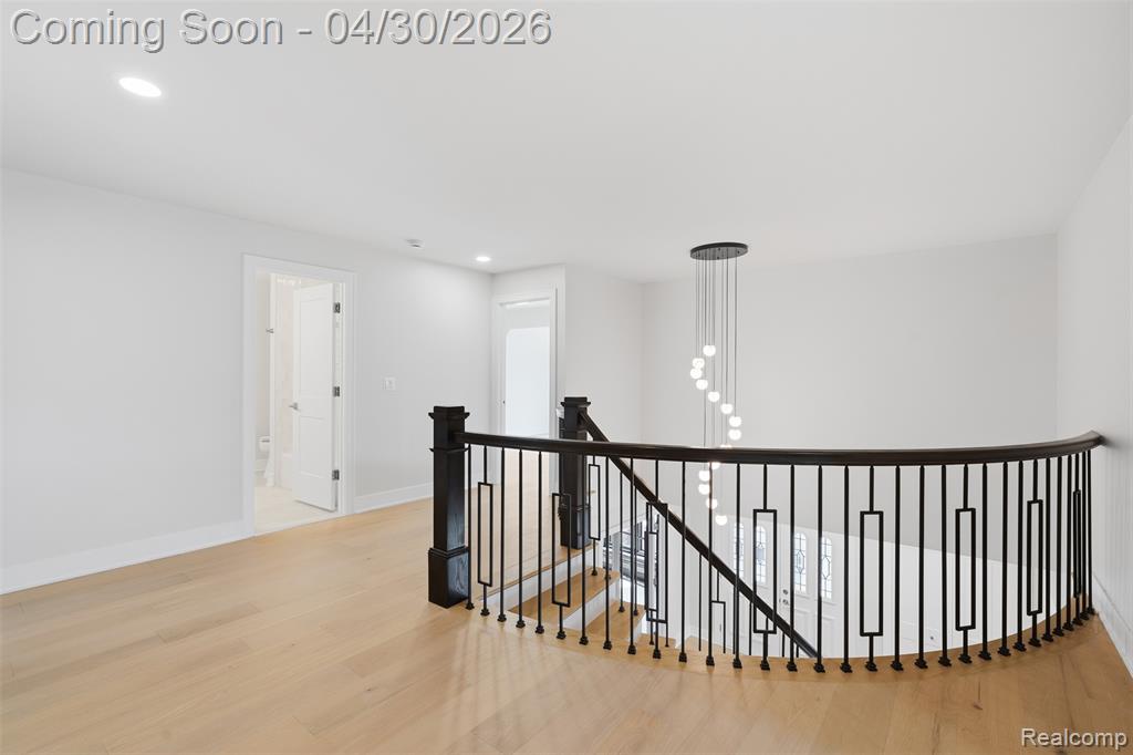 Hallway featuring an upstairs landing, light wood-style floors, and recessed lighting