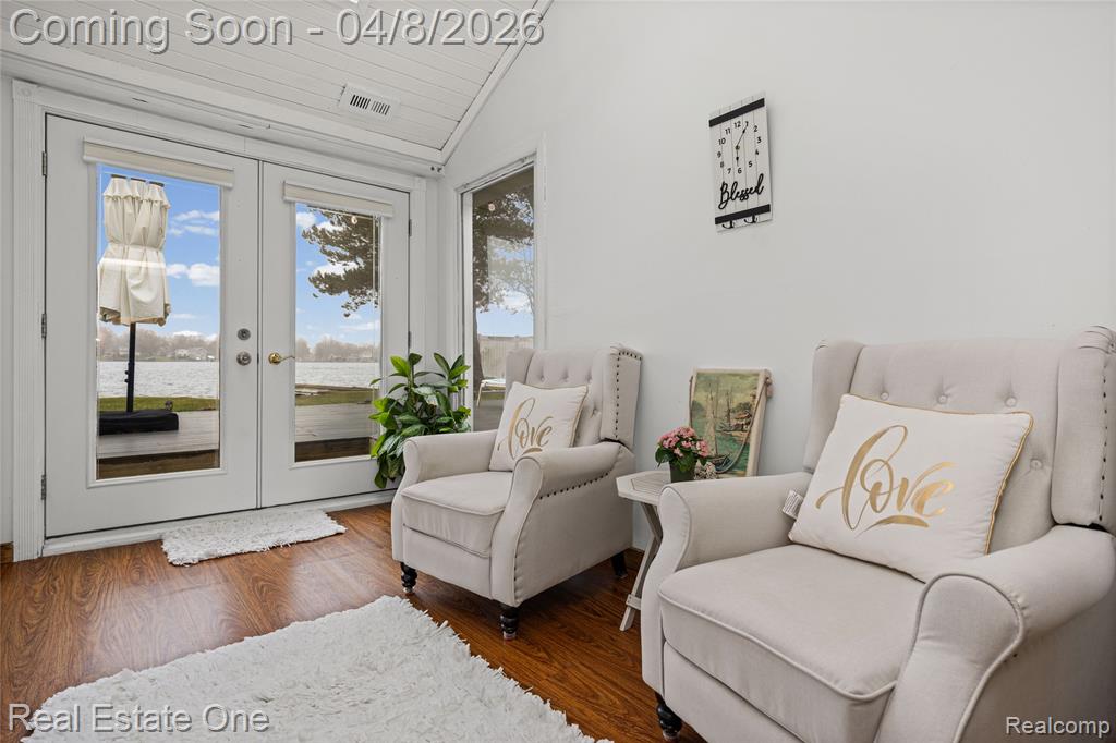 Sitting room featuring french doors, wood finished floors, vaulted ceiling, and a water view