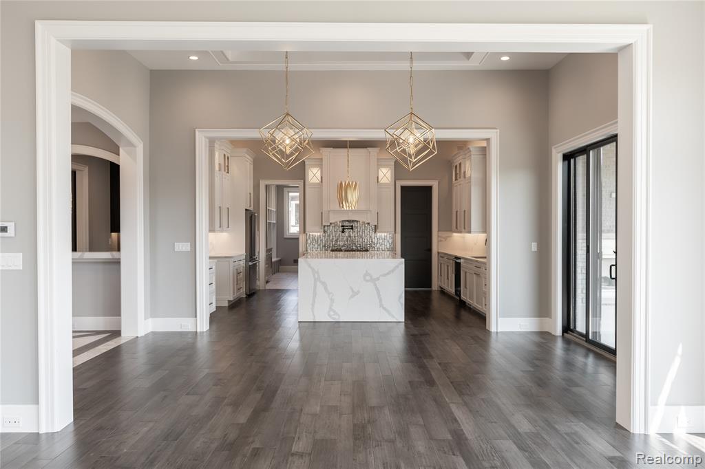 Kitchen featuring hanging light fixtures, light stone counters, dark wood-style floors, and white cabinets