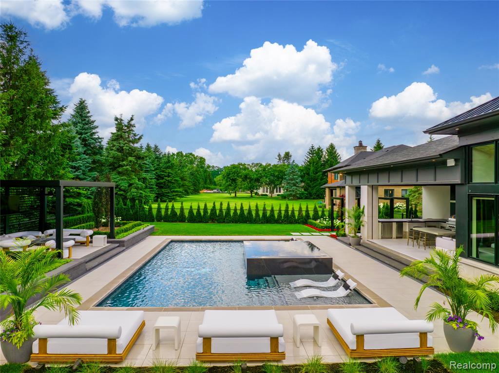 Swimming pool featuring a patio, view of scattered trees, an outdoor living space, and a lawn