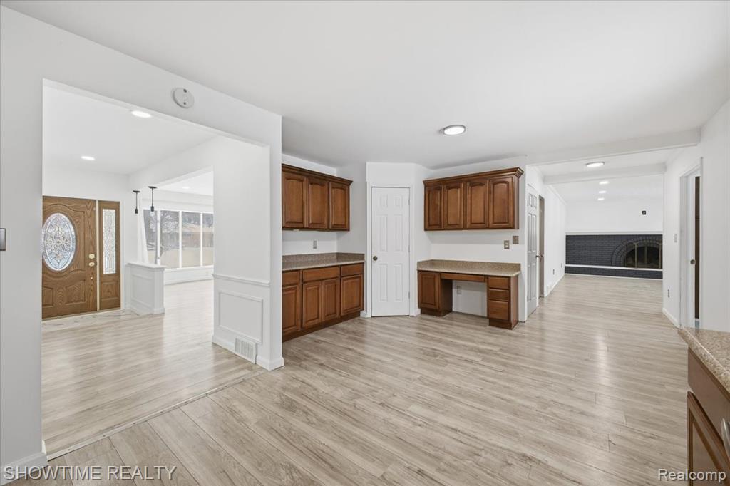 Kitchen with light wood-style flooring, built in desk, recessed lighting, wainscoting, and open floor plan