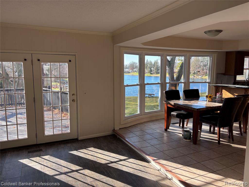 Dining room featuring a water view, crown molding, and dark wood finished floors