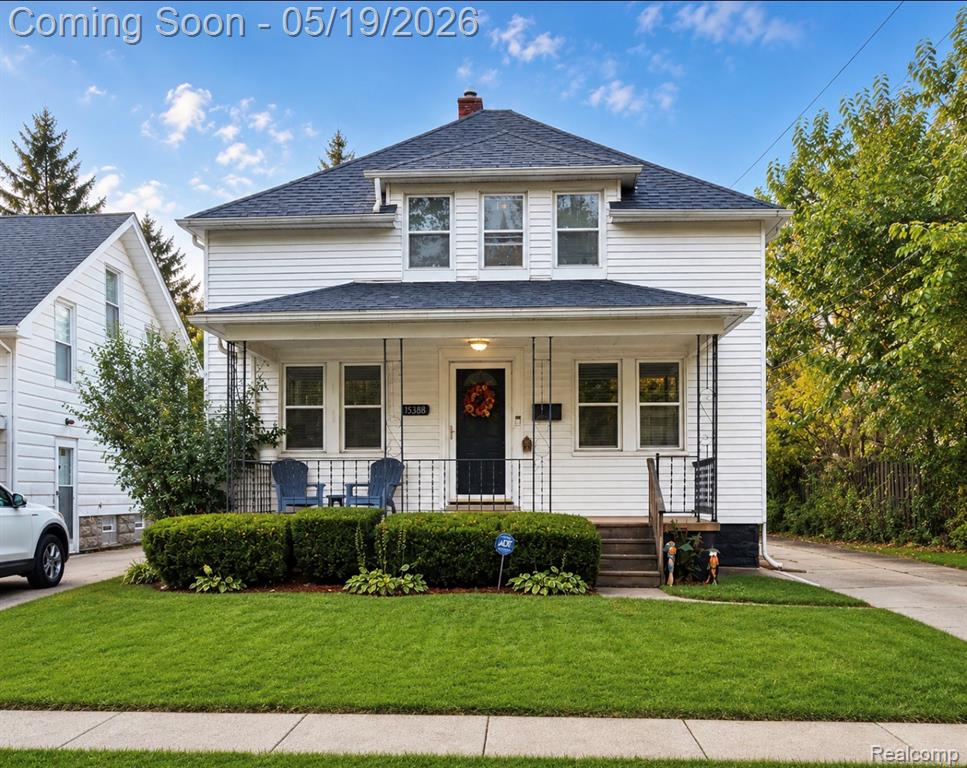 View of front of house featuring covered porch, a front yard, roof with shingles, and a chimney