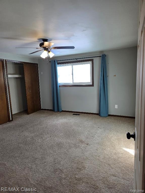 Unfurnished bedroom featuring light colored carpet and ceiling fan