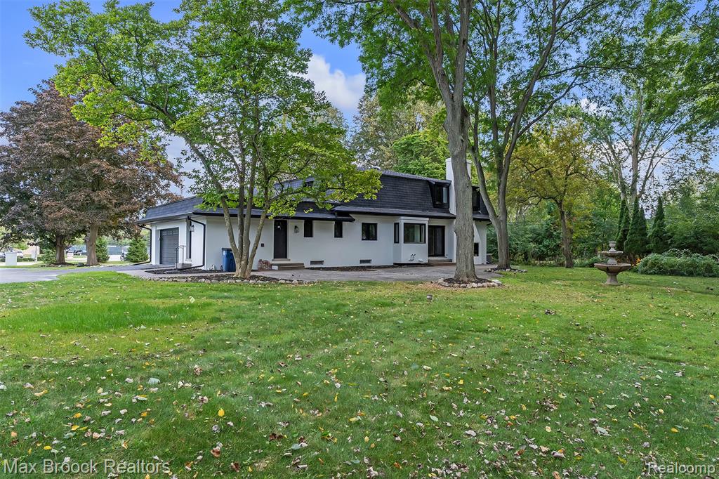 View of front of home featuring a shingled roof, a garage, a front yard, and a patio area