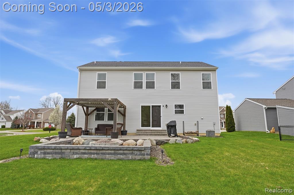 Back of property with a pergola, a patio, a yard, and a fire pit