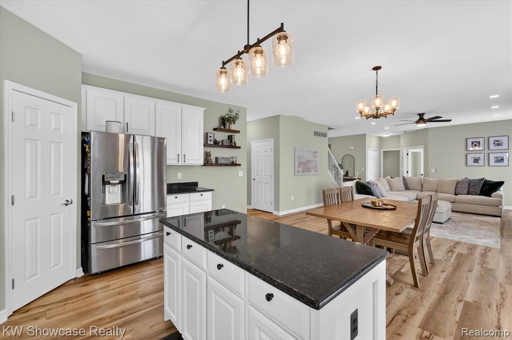 Kitchen with dark countertops, white cabinetry, pendant lighting, and appliances with stainless steel finishes