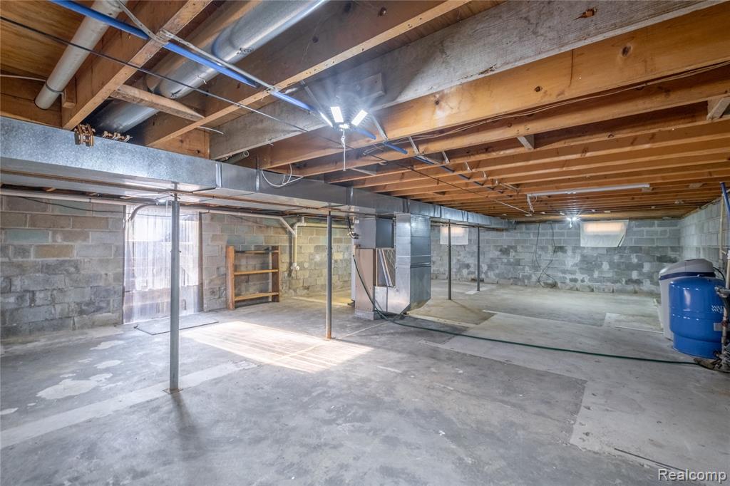 Unfinished basement featuring heating unit and a water pressure tank