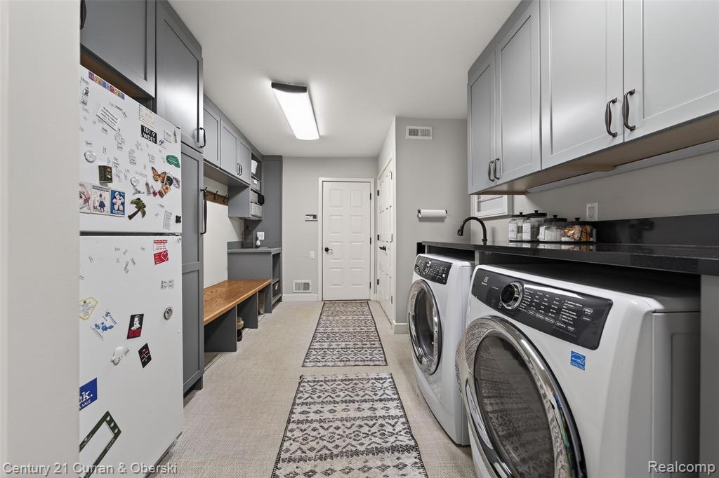Laundry area with independent washer and dryer, light floors, and cabinet space