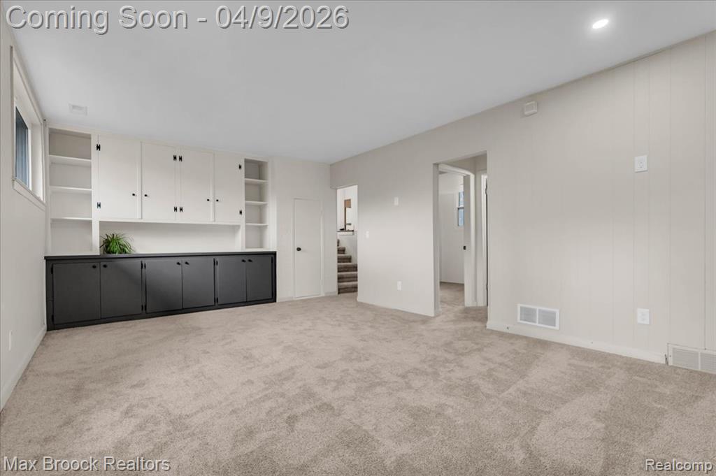 Unfurnished living room with light colored carpet and baseboards
