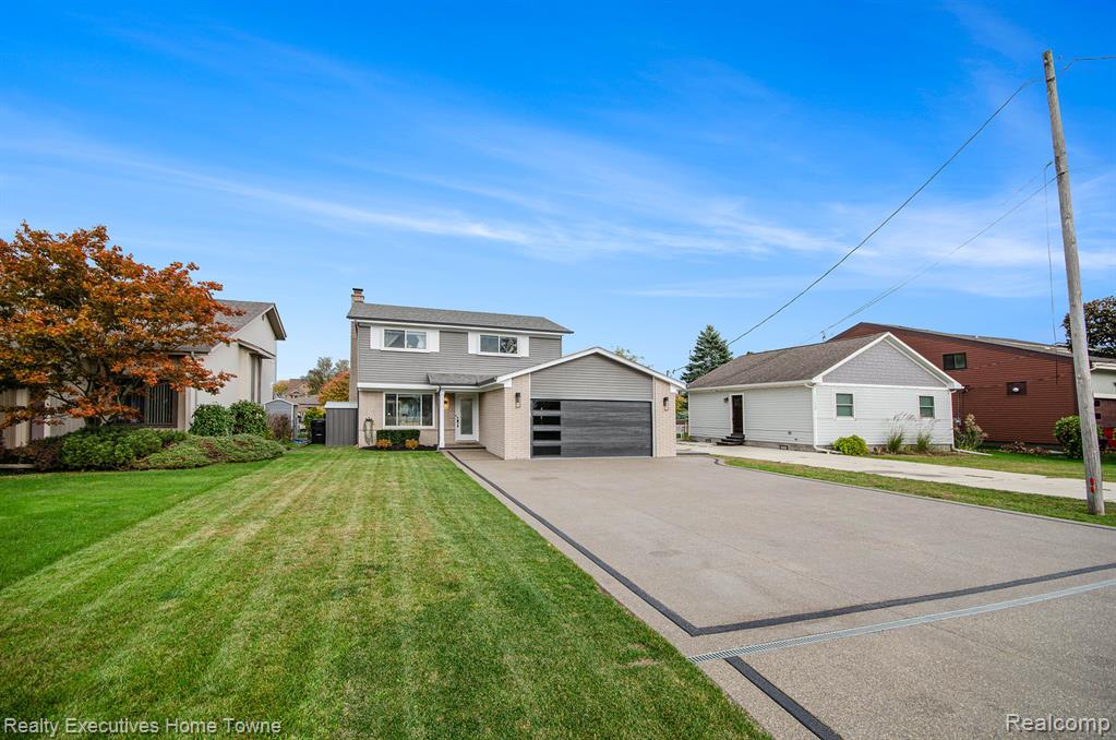 View of front of house with a front yard, driveway, and a garage